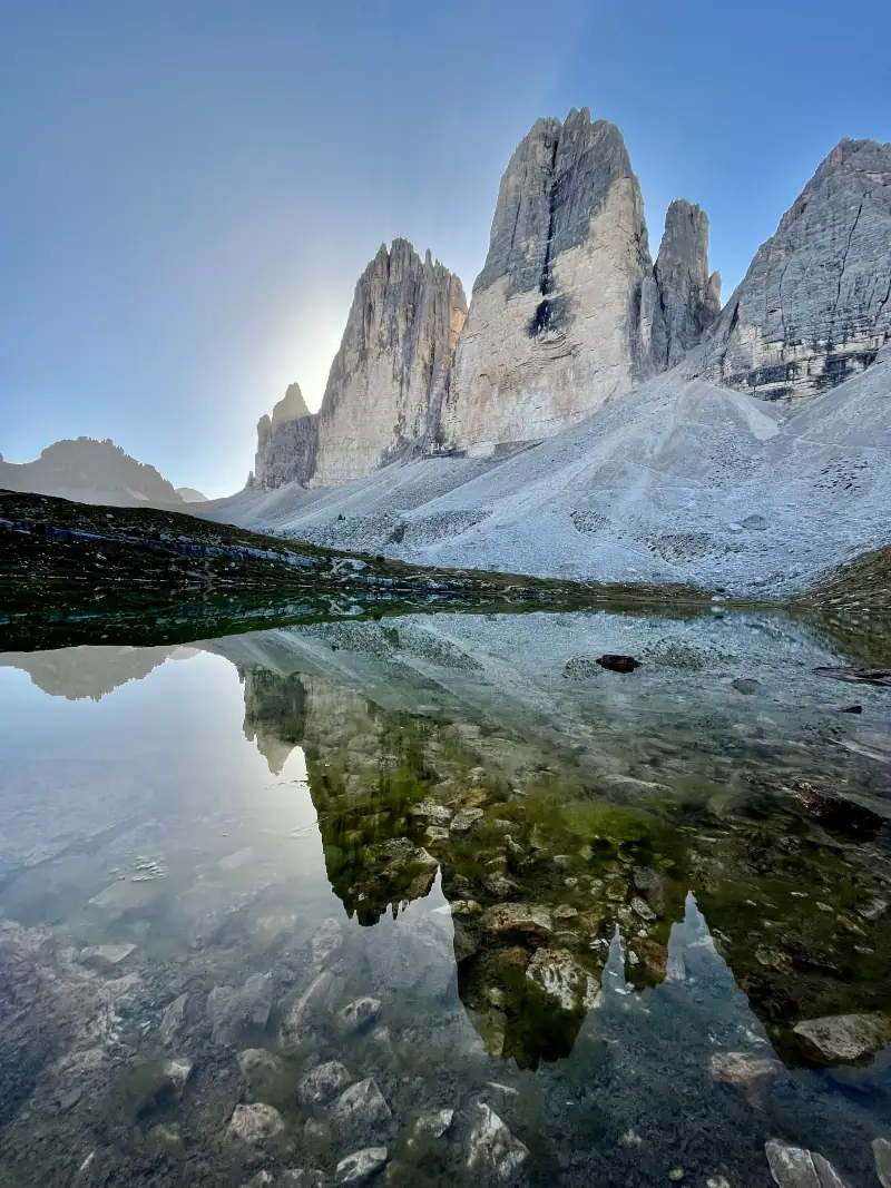 Tre Cime reflected in a small alpine lake.